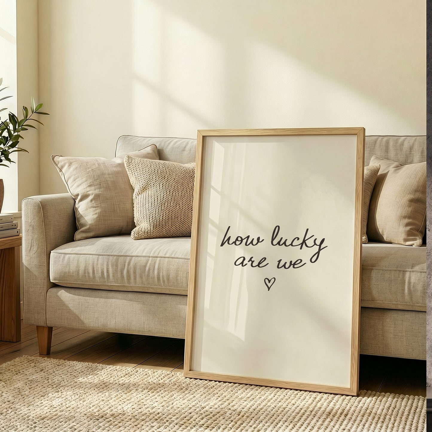 Framed neutral wall art with the quote how lucky are we hanging on a wall, reflecting a bright room window.