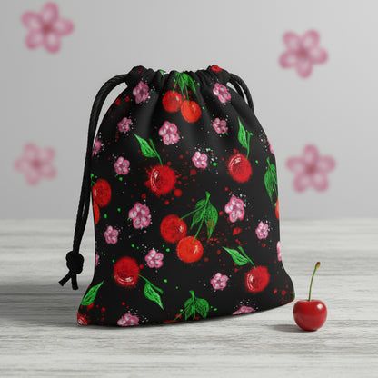 "Mockup of a black fabric drawstring pouch featuring a vibrant cherry and floral print on a wooden table."