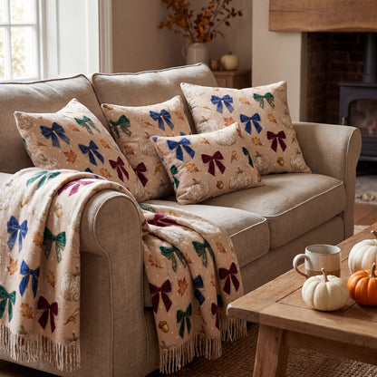 Mockup of a cozy living room with throw pillows and a blanket featuring a vintage fall pattern with velvet bows and pumpkins.