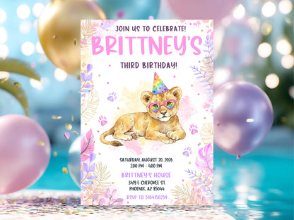 Watercolor girl's lion birthday invitation featuring a lion cub with rainbow heart glasses and party hat, surrounded by pink and purple tropical leaves and gold accents.
