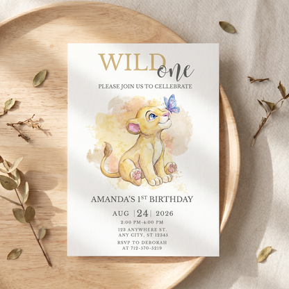 Safari themed Wild One 1st birthday invitation printed and placed on an elegant party table setting.