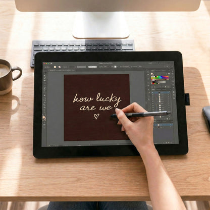 Digital artist creating hand-drawn typography for a "how lucky are we" dark brown digital poster on a drawing tablet