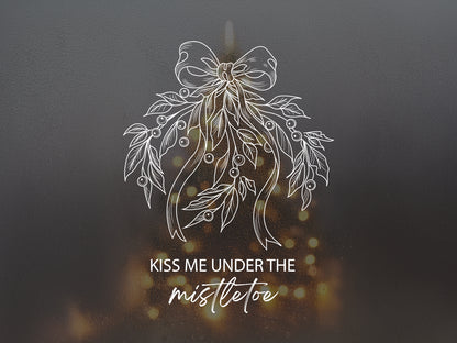 White line art illustration of mistletoe with a bow and text Kiss Me Under The Mistletoe.
