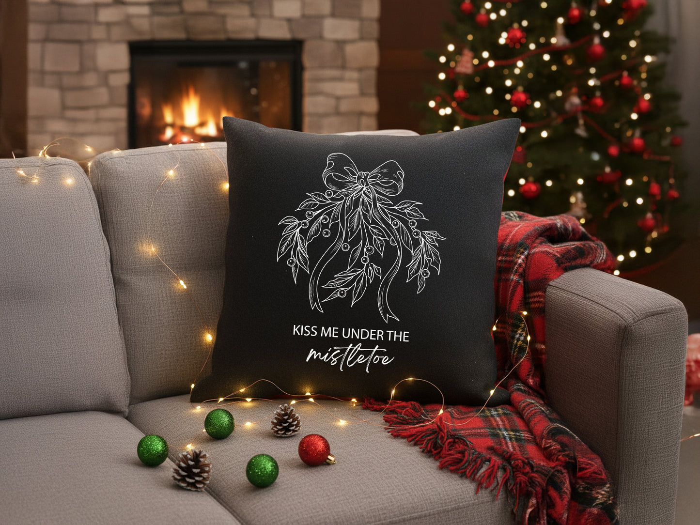 Black holiday throw pillow with white mistletoe vinyl design on a sofa.

