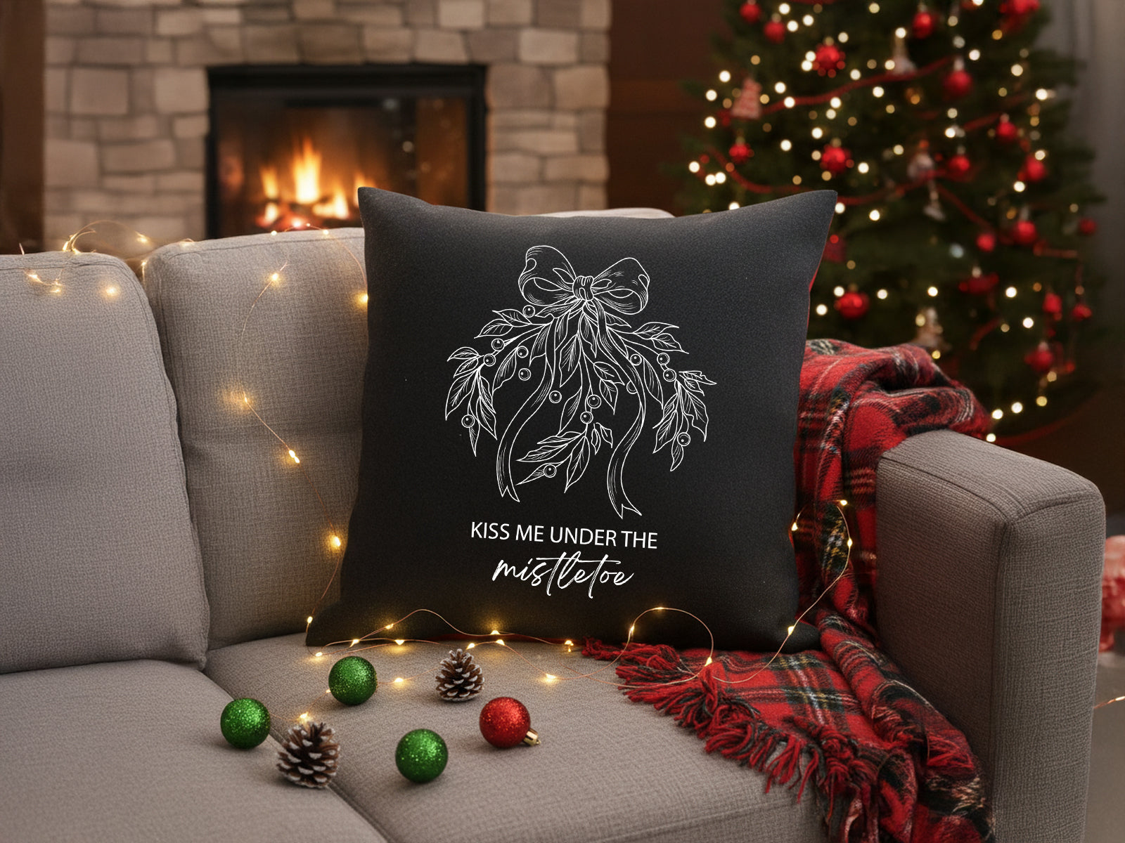 Black holiday throw pillow with white mistletoe vinyl design on a sofa.

